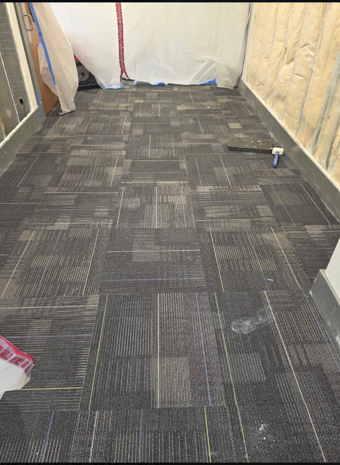 Newly installed commercial carpet tile with dust containment barrier in the background