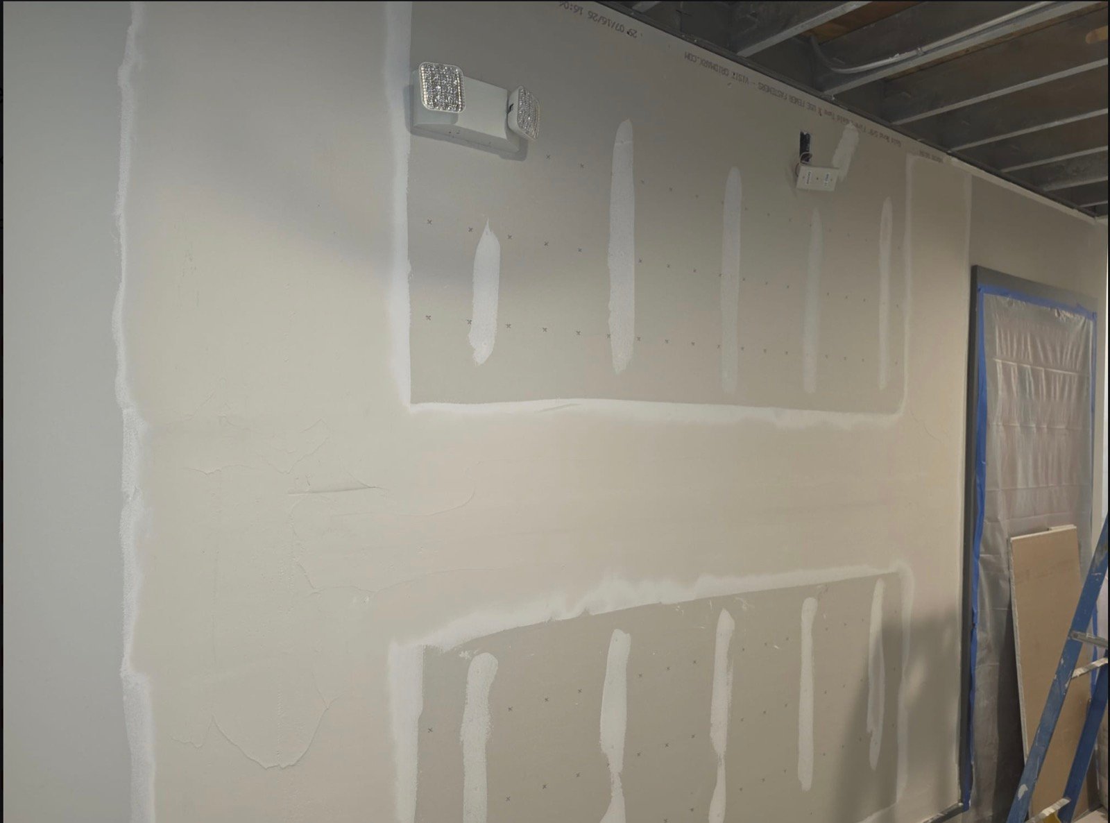 Drywall wall with joint compound coats feathered over taped seams and screw heads