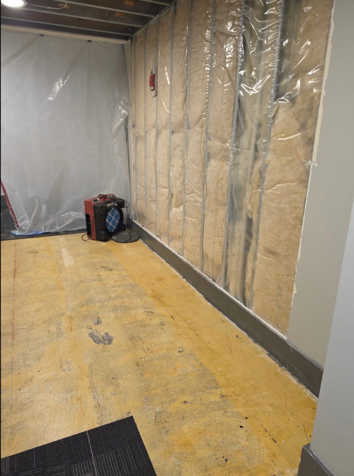 Batt insulation with vapor barrier installed between metal studs, air scrubber running