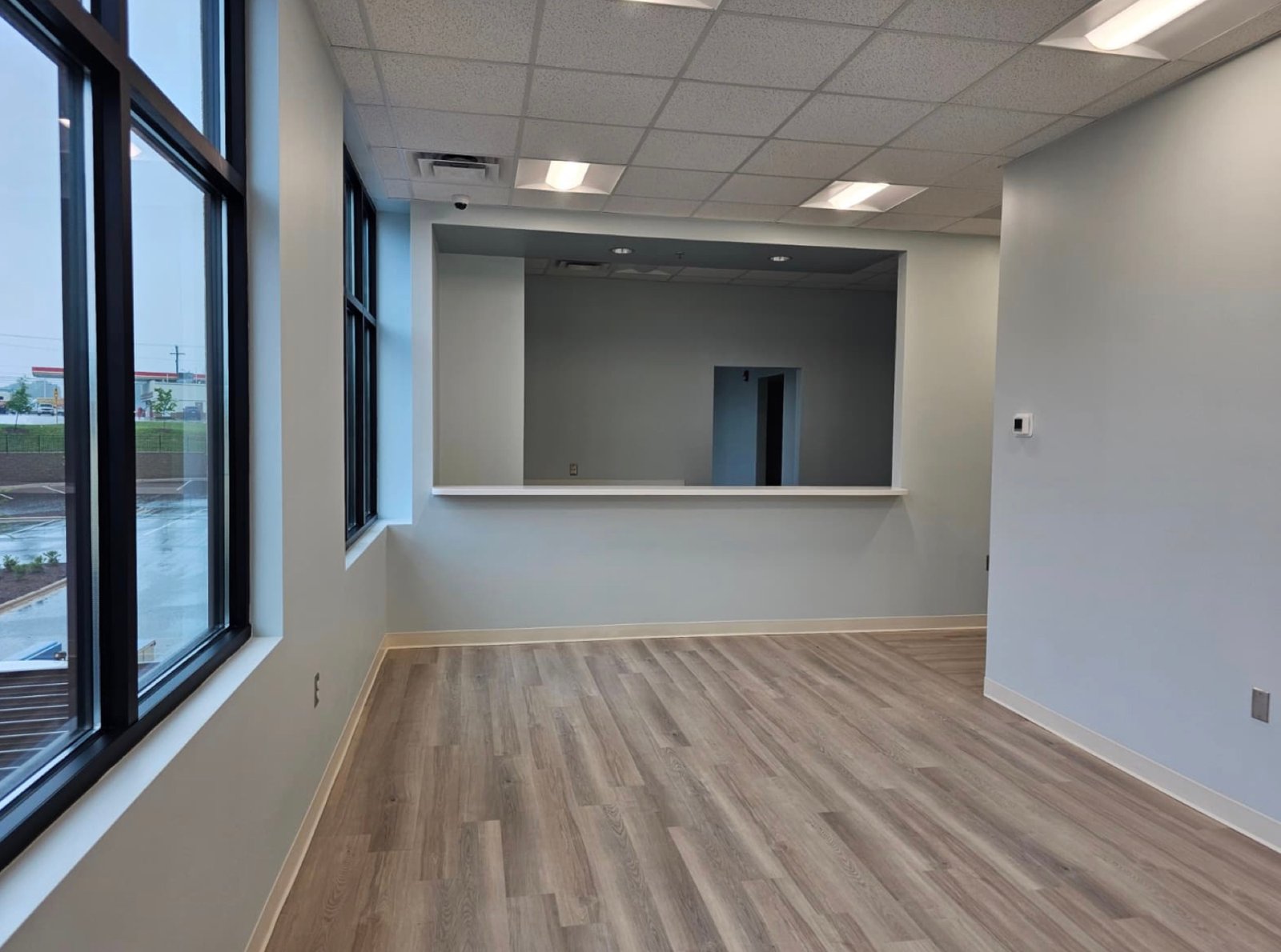 Finished commercial office with luxury vinyl plank flooring, suspended ceiling and a pass-through service window